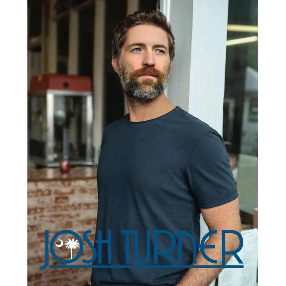 Man with a beard wearing a dark blue t-shirt.