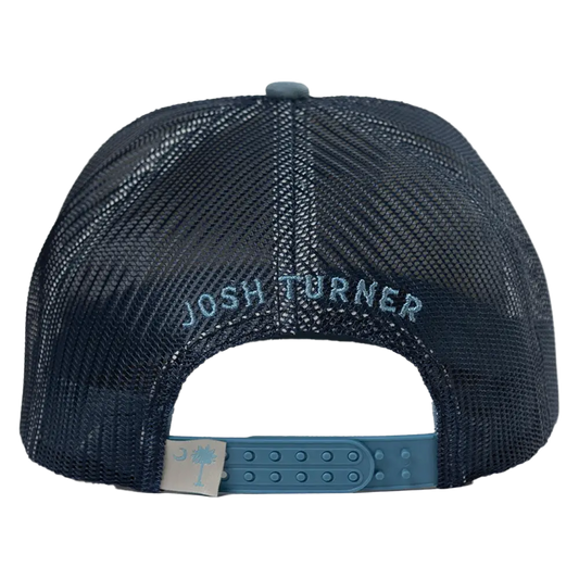Dark navy mesh trucker hat with ’josh turner’ embroidered in light blue thread and a matching teal plastic adjustable strap featuring a beige tag with a pale blue palmetto tree logo.
