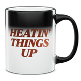 Coffee mug with the phrase ’HEATIN’ THINGS UP’ printed on it in reddish-brown text.