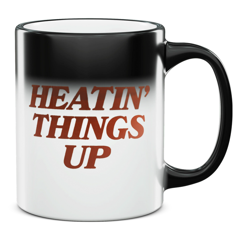 Coffee mug with the phrase ’HEATIN’ THINGS UP’ printed on it in reddish-brown text.