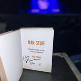 A signed hardcover copy of ’man stuff’ by josh turner, featuring orange text on a white page with the author’s signature below.