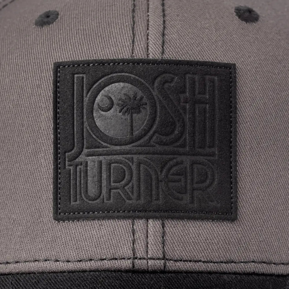 Gray baseball cap with a black embroidered patch featuring the text ’JOSH TURNED’.