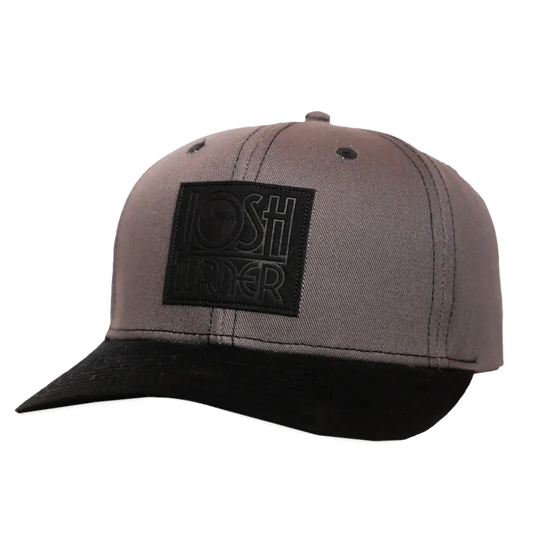 A taupe-colored baseball cap with a black embroidered patch featuring the ’lost under’ logo.