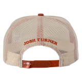 Cream-colored mesh trucker hat with orange embroidered ’josh turner’ text and a matching orange adjustable strap featuring a white crescent moon and palmetto tree logo.