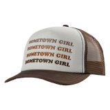 Trucker-style cap with ’HOMETOWN GIRL’ repeated in brown text on a white front panel and brown mesh back.