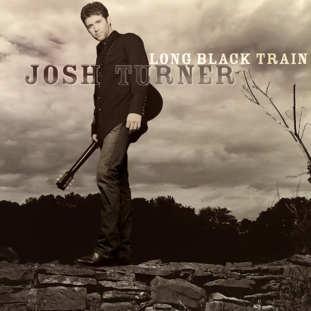 Album cover featuring a man standing on rocky ground holding a guitar, with the text ’JOSH TURNER LONG BLACK TRAIN’ visible.