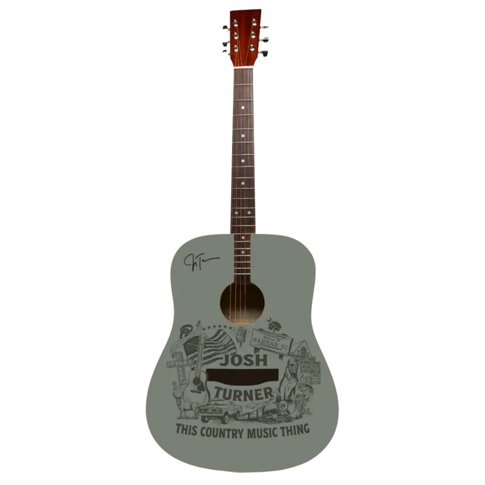A light gray acoustic guitar with a detailed black-and-white graphic design featuring ’josh turner’ and the phrase ’this country music thing,’ along with an autograph on its body.