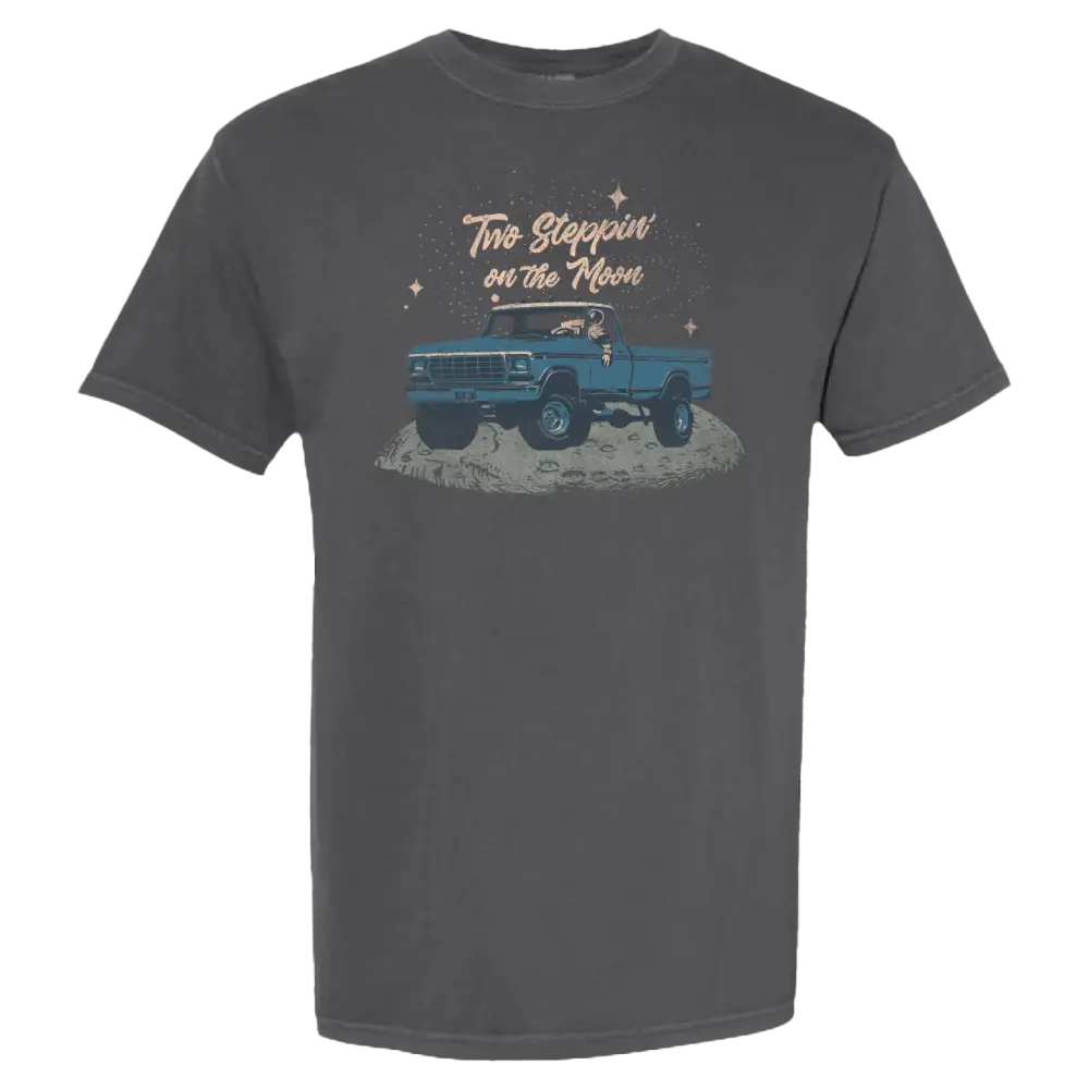 Dark gray t-shirt featuring a cartoon illustration of a blue pickup truck on the moon with the text ’two steppin’ on the moon’ above it.